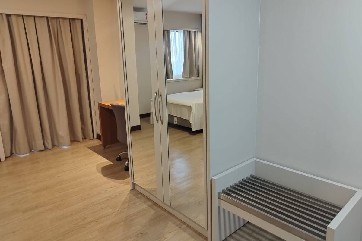 A room with a sliding glass door, a bed, a desk, and a radiator.