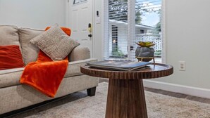 A living room with a sofa, a small round wooden table, and a door with a window in the background. - Peaceful APT by Lakebottom w Arcade/8mi FT Benning (Columbus)