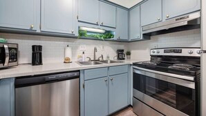 A kitchen with light blue cabinets, stainless steel appliances, a dishwasher, and a built-in oven. - Peaceful APT by Lakebottom w Arcade/8mi FT Benning (Columbus)