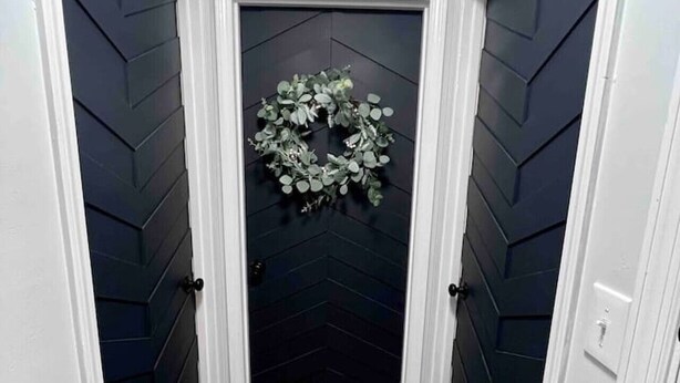Un pasillo con paredes de madera oscura y una puerta negra.