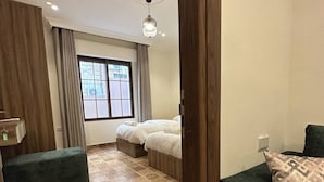 A hotel room with a bed, a green sofa, a patterned floor, a window with curtains, and a ceiling light. - 3 Antica Jabalal-lwebdeh (Amman)