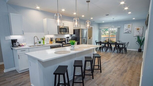 A modern kitchen with a central island, bar stools, and pendant lighting. - Escape to 4BR/3BA Brand New Downtown Home (San Antonio)
