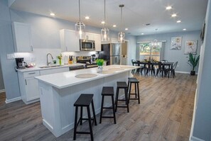 Une cuisine moderne dotée d’un îlot central, de tabourets de bar et de luminaires suspendus.