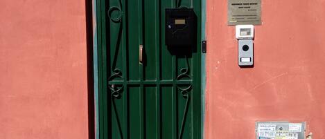 A green door with a metal gate, a number plate, and a sign indicating Andeni Timber House Room 2 Category.