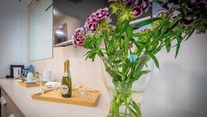 A hotel room with a wooden counter, a bottle of wine, a glass, and a vase with flowers. - Andenis Tiber House  (Rome)