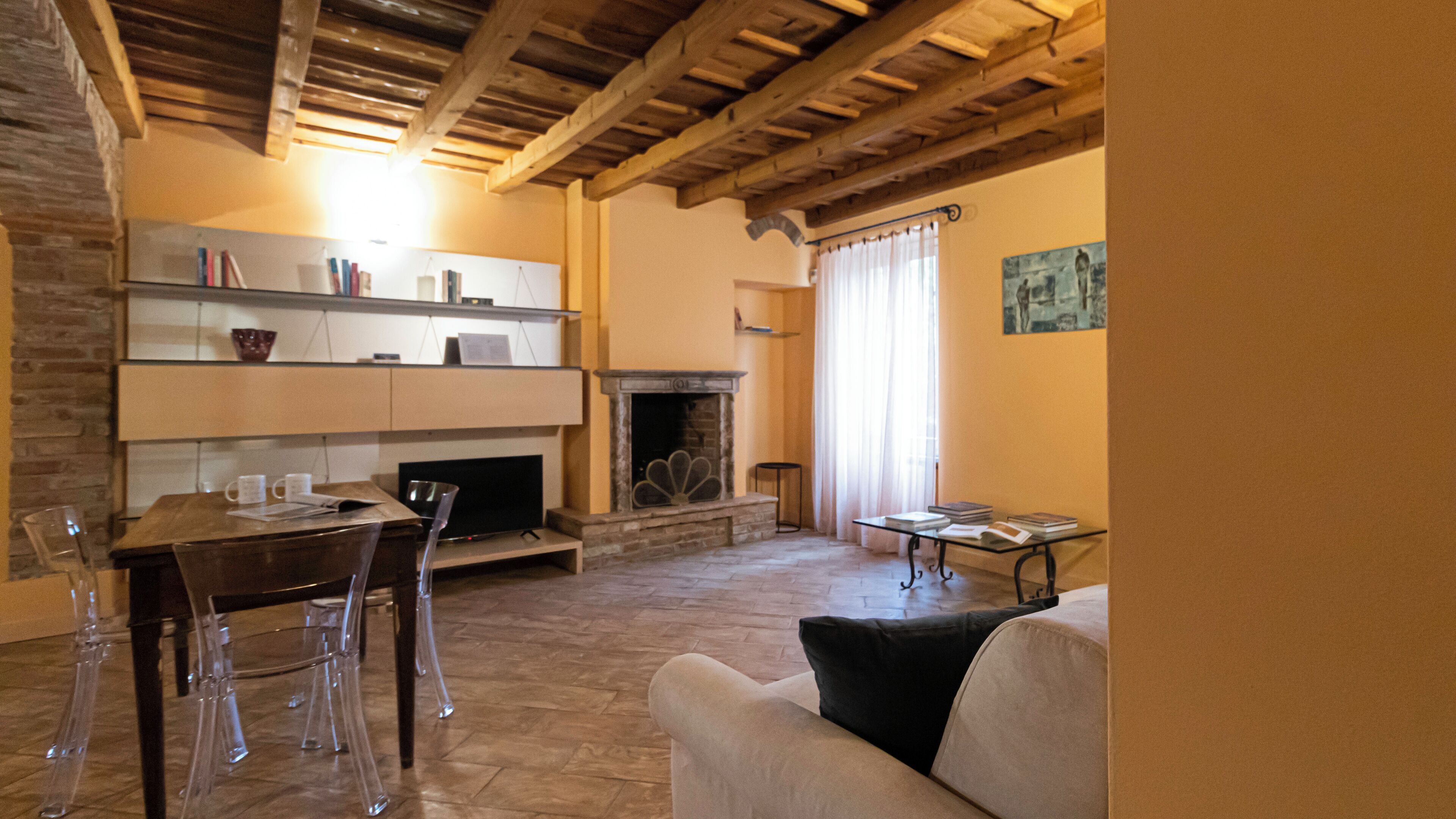 A cozy living room with a fireplace, a dining table with chairs, and a sofa.