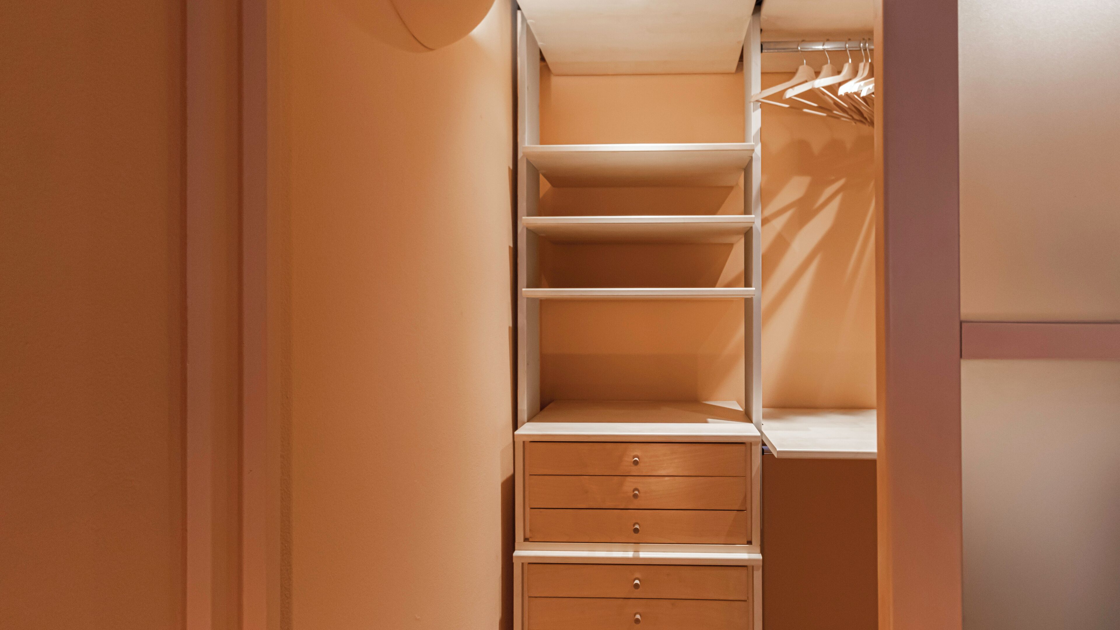A walk-in closet with open shelves, hanging space, and drawers.