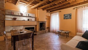A cozy living room with a fireplace, a dining area with a table and chairs, and a sofa. - Italianway Easy - Garibaldi 93 B (Milan)