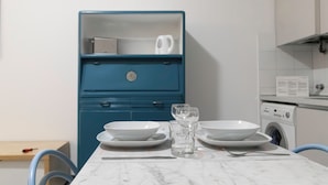 Eine Küche mit Marmorarbeitsplatte, einem blauen Schrank und einer Waschmaschine.