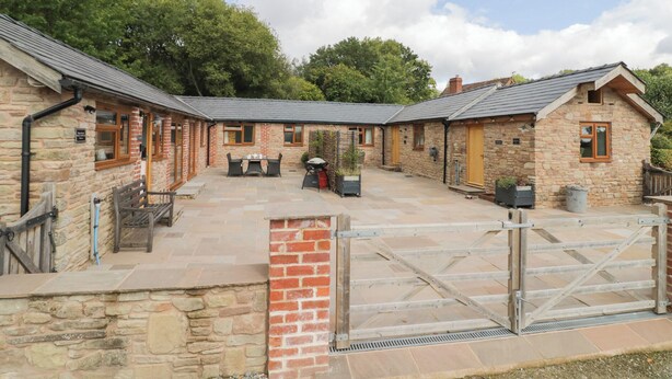 A stone building with a courtyard, featuring a grill area and outdoor seating. - Keepers Barn (Worcester)