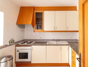 A kitchen with white cabinets, a stove, and a sink. - 54 Golfmar Carvoeiro apartment with fabulous pool (Carvoeiro)
