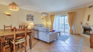 A living room with a wooden dining table, a sofa, and a fireplace. - 61B  Apartment in the Heart of Gramacho Gof Complexo (Estômbar)