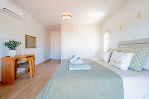 A bedroom with a bed, bedside table, mirror, and a potted plant.