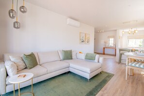 A living room with a sectional sofa, a small round table, and a dining area with a table and chairs.