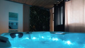 Un jacuzzi con panel de control, rodeado por un techo de madera y una pared con jardín vertical.