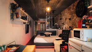 Une chambre moderne avec un lit, une table de chevet et un four à micro-ondes.