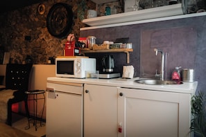 A compact kitchen with a microwave, coffee maker, and a sink.