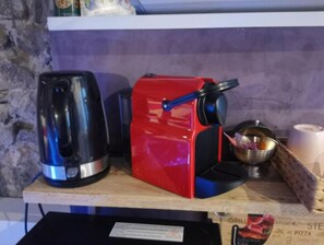 Uma cozinha com um eletrodoméstico vermelho, um eletrodoméstico preto e uma tigela de metal sobre uma superfície de madeira.