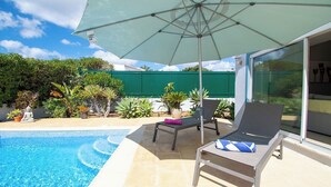 A poolside area with a lounge chair, umbrella, and potted plants. - Ana- Beautiful villa in walking distance of Carvoeiro with Heated Private Pool (Carvoeiro)