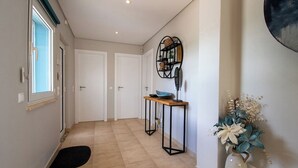A hallway with a wooden floor, a black doormat, a small table with a bowl, and a vase with flowers. - Ana- Beautiful villa in walking distance of Carvoeiro with Heated Private Pool (Carvoeiro)