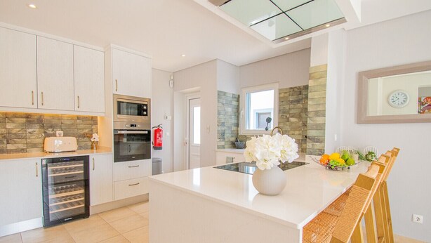 A modern kitchen with white cabinetry, a built-in oven, and a refrigerator. - Ana- Beautiful villa in walking distance of Carvoeiro with Heated Private Pool (Carvoeiro)