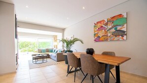 A modern living room with a wooden dining table, comfortable seating, and a large fish-themed artwork on the wall. - Ana- Beautiful villa in walking distance of Carvoeiro with Heated Private Pool (Carvoeiro)