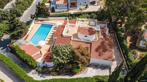 An aerial view of a property with a swimming pool, outdoor seating area, and a covered patio.
