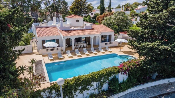 A poolside area with a swimming pool, sun loungers, and a covered seating area.