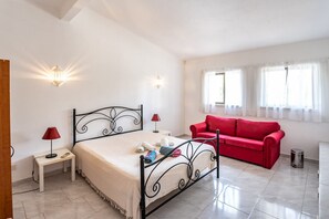Relax in a serene bedroom with a comfortable bed, sofa, and ample natural light.