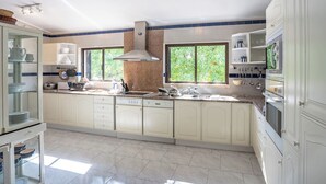 A spacious kitchen with white cabinets, a stainless steel range hood, and a large window providing natural light.