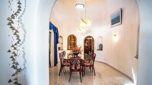 A dining area with a round table and chairs, a chandelier, and a view of the outside.