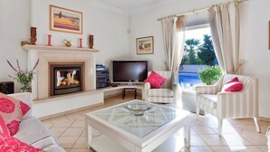A living room with a fireplace, television, and striped armchairs.