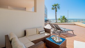 En balkon med fletmøbler, et bord med bakke og havudsigt.