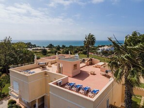 A rooftop terrace with lounge chairs and a view of the sea. - 11 marinha Two Bedroom Apt at Praia do Marinha (Carvoeiro)