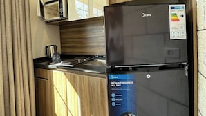 A kitchen with a black refrigerator, a microwave, and wooden cabinets. - Antica Jabalal-lwebdeh (Amman)