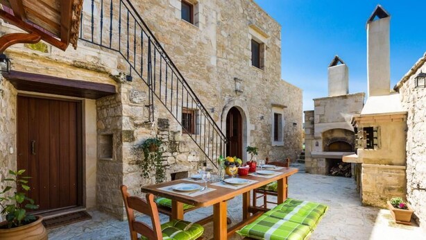 A stone building with a wooden staircase, a dining table with chairs, and a bench. - Ani Villa, authentic Cretan lifestyle (Rethymno)