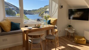 Quarto aconchegante com uma grande janela e vista panorâmica da costa.