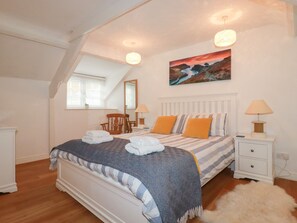 A bedroom with a bed, two bedside tables, a chair, a painting, and a window. - Harbour Light (Boscastle)