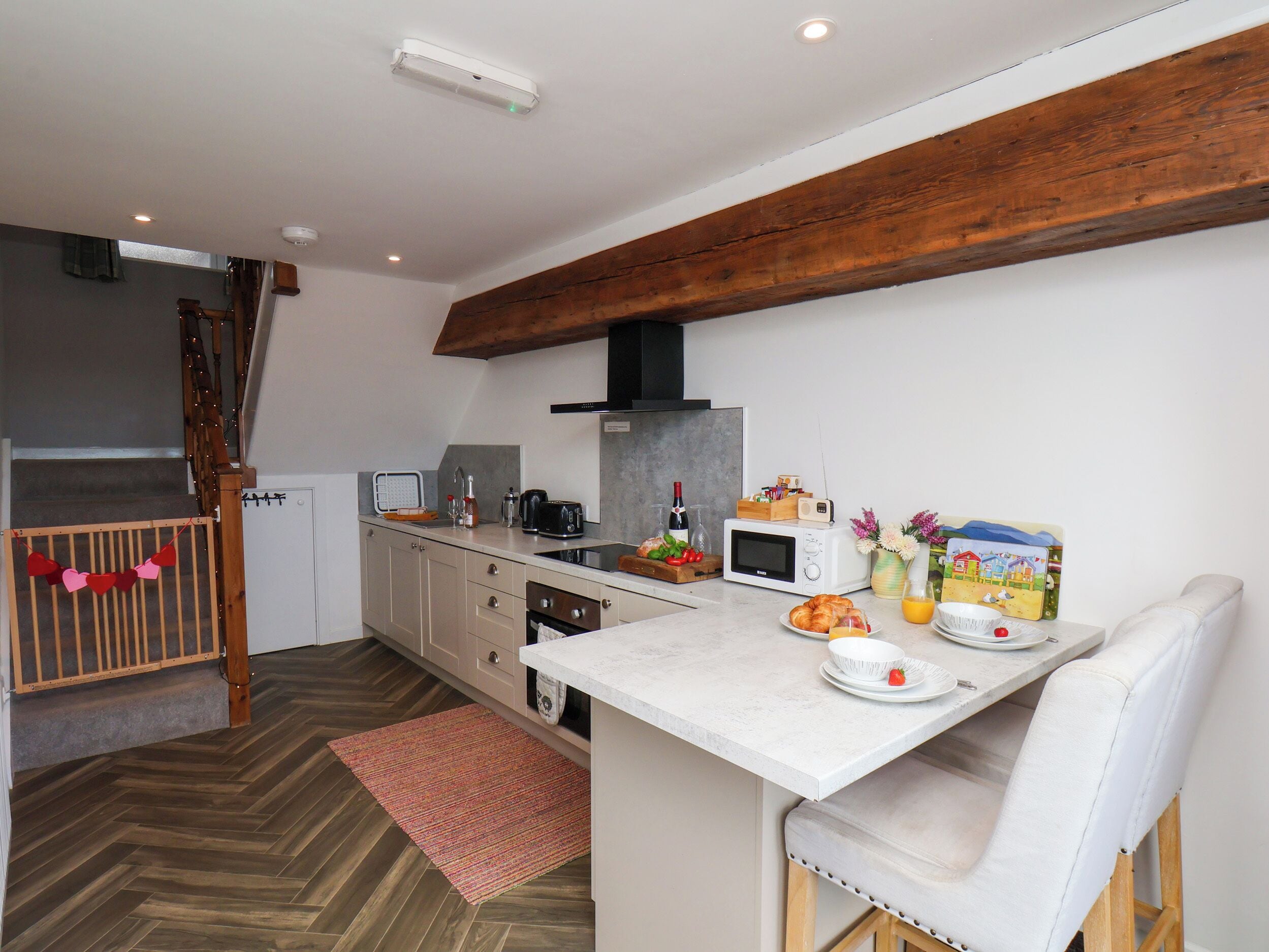 Eine moderne Küche mit Holzbalkendecke, einer Mikrowelle, einem Toaster und einem Essbereich mit einem weißen Stuhl.