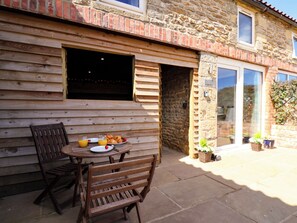 A wooden table with chairs and breakfast items outside a stone building with a window. - Hawthorn Cottage (Scarborough)