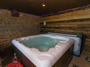 Een bubbelbad met een houten wand en een bakstenen muur op de achtergrond.