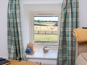 A room with a window overlooking a fenced field with animals. - Hawthorn Cottage (Scarborough)