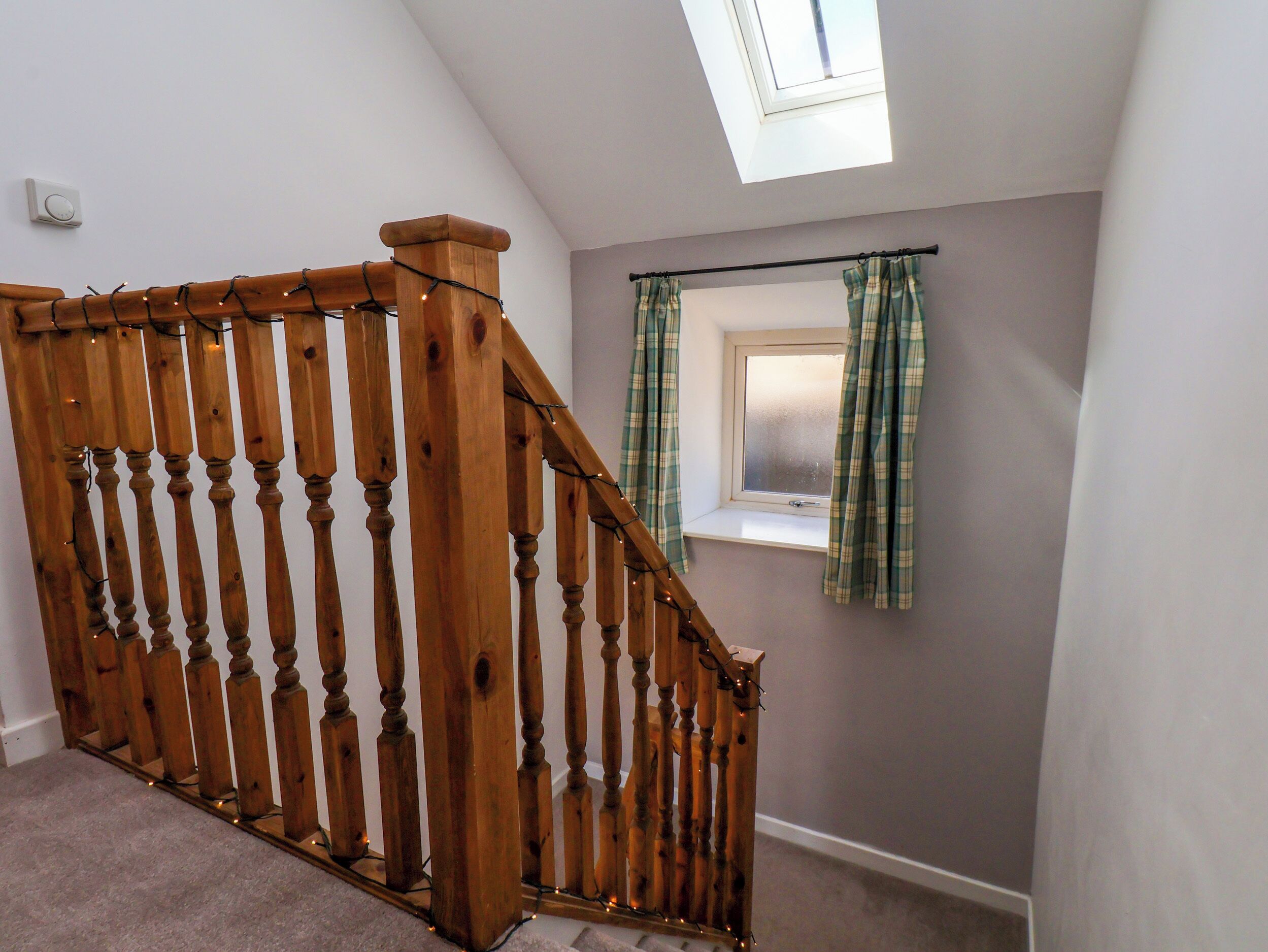 A wooden staircase with a glass ceiling and a window with curtains.