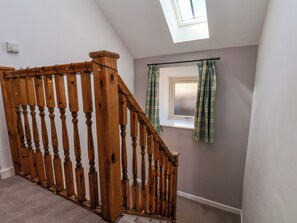 Un escalier en bois, avec un plafond en verre et une fenêtre ornée de rideaux.