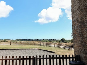 A fenced outdoor area with a gravel path, a wooden fence, and a stone wall. - Hawthorn Cottage (Scarborough)