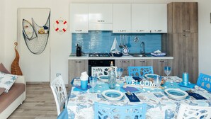 Una cocina moderna con armarios blancos, salpicadero azul y decoración náutica.