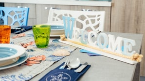 Una mesa dispuesta con un letrero de bienvenida, un vaso verde, platos y cubiertos.