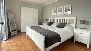 A bedroom with a bed, bedside tables, a wardrobe, and a mirror. - Boardinghouse - Apartment (Lippstadt)