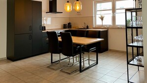 A modern kitchen with a central island, black cabinets, and pendant lighting. - Boardinghouse - Apartment (Lippstadt)
