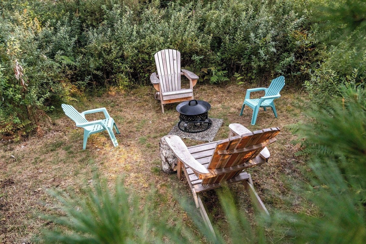 Un espace extérieur aménagé avec des chaises Adirondack et un foyer.